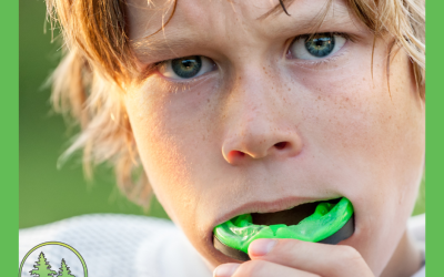 Young athlete putting in a green sports mouthguard, close-up of face with intense expression, wearing white sports gear — promoting custom mouthguards at Spring Hill Dental.