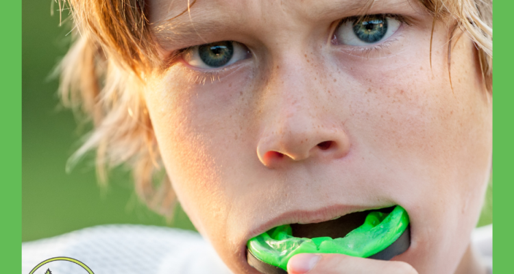 Young athlete putting in a green sports mouthguard, close-up of face with intense expression, wearing white sports gear — promoting custom mouthguards at Spring Hill Dental.
