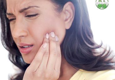 Woman touching her jaw in discomfort, showing signs of TMJ pain.