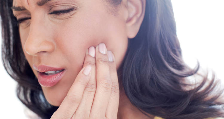 Woman touching her jaw in discomfort, showing signs of TMJ pain.