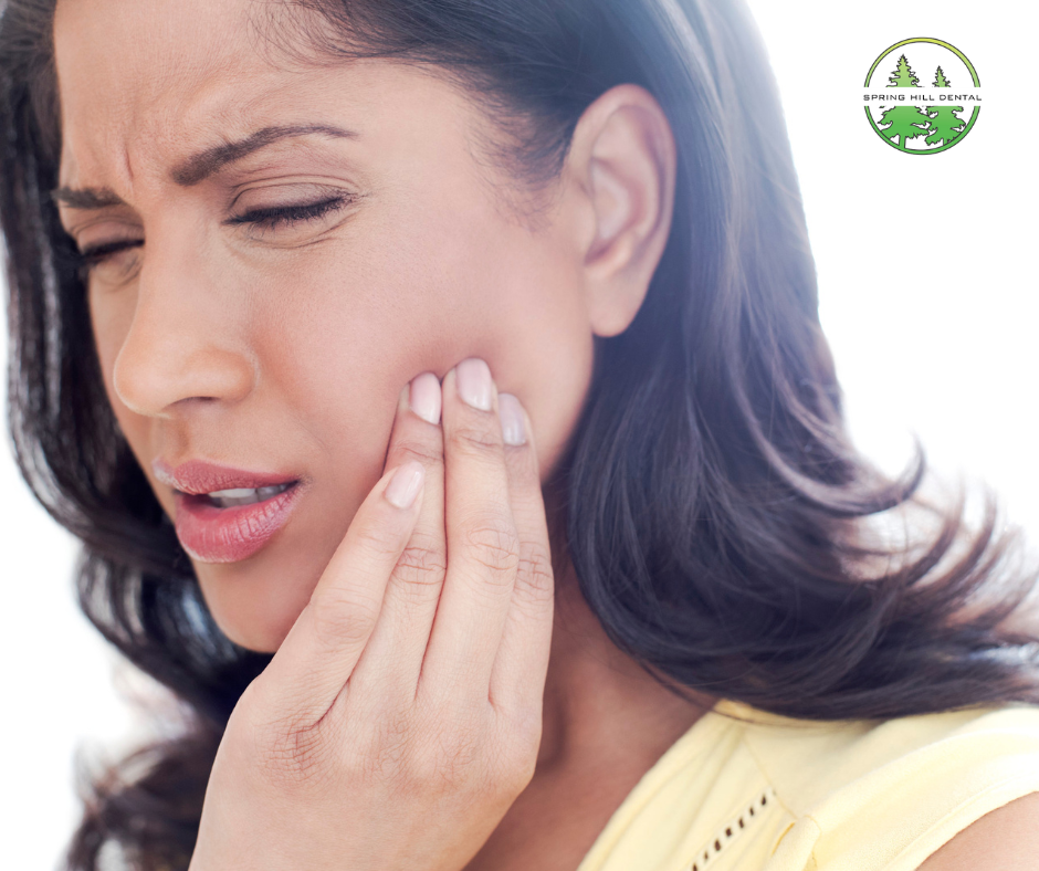 Woman touching her jaw in discomfort, showing signs of TMJ pain.
